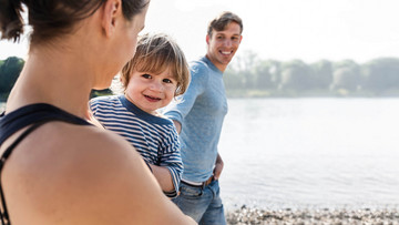 Mutter, Vater und Sohn spazieren am Flussbett