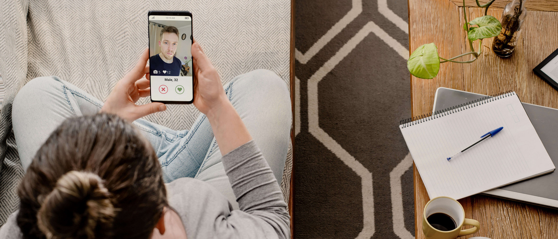 Eine Frau sitzt auf der Couch und schaut die Fotos in einer Dating App auf Ihrem Smartphone durch.