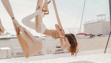 Junge Frau beim Aerial Yoga am Strand