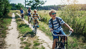 Kinder fahren glücklich mit dem Fahrrad auf einem Feldweg