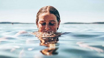Frau schwimmend in einem See, der Kamera zugewandt